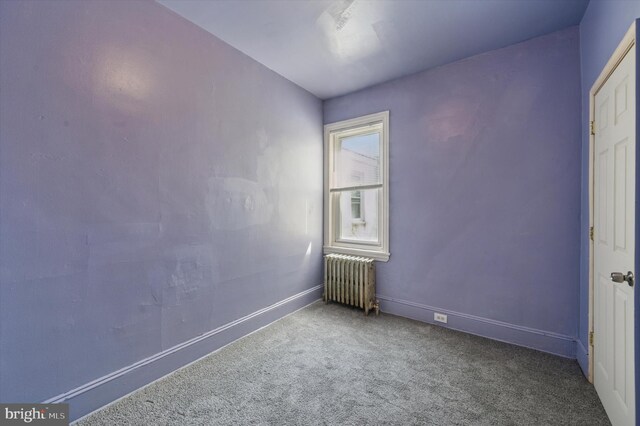carpeted empty room with radiator heating unit and baseboards