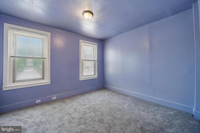 carpeted spare room featuring baseboards
