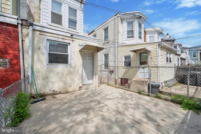 view of front facade with fence, central AC, and a patio