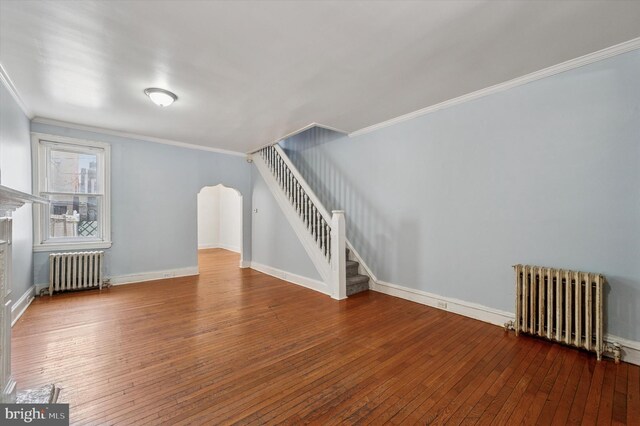 additional living space with radiator, stairs, baseboards, and wood-type flooring