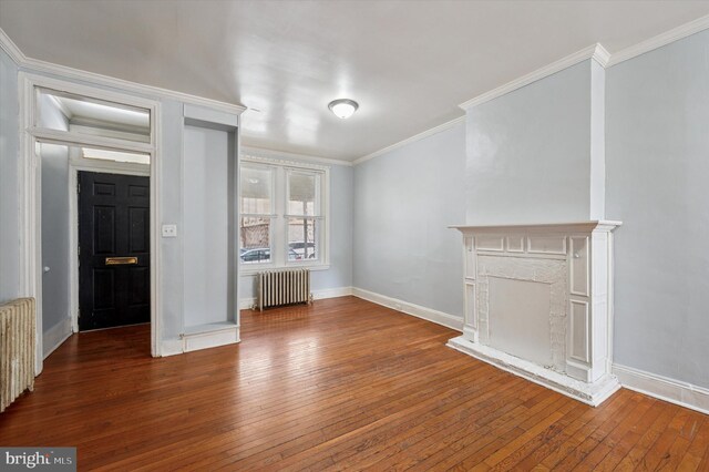 unfurnished living room featuring radiator, crown molding, hardwood / wood-style flooring, and baseboards