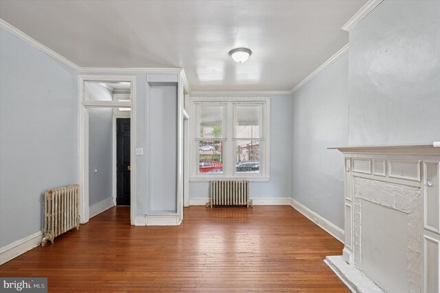 unfurnished bedroom featuring ornamental molding, radiator heating unit, hardwood / wood-style flooring, and baseboards