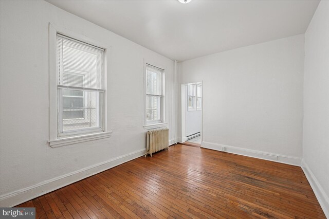 spare room with hardwood / wood-style floors, radiator heating unit, a baseboard heating unit, and baseboards