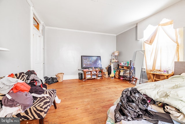 bedroom with baseboards, ornamental molding, and wood finished floors