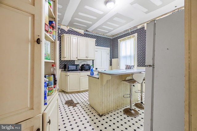 kitchen featuring a toaster, a breakfast bar, wallpapered walls, and light tile patterned flooring