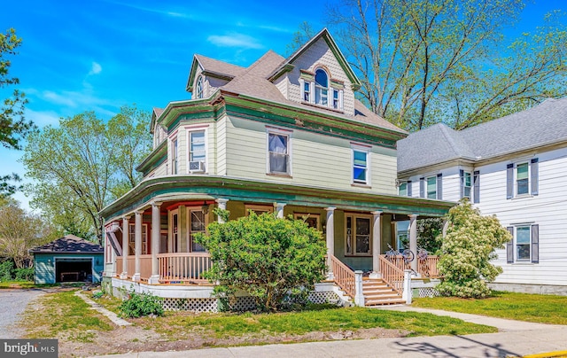 victorian house featuring a garage, covered porch, an outbuilding, and driveway