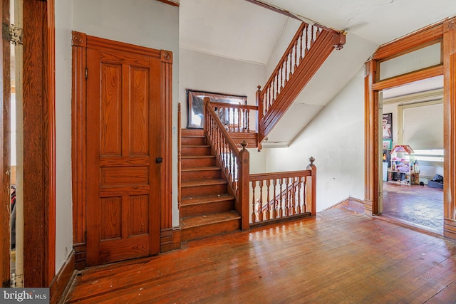 stairs featuring wood-type flooring and lofted ceiling