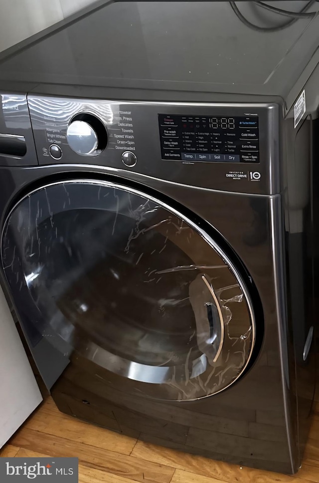 laundry view of washer / dryer and wood finished floors
