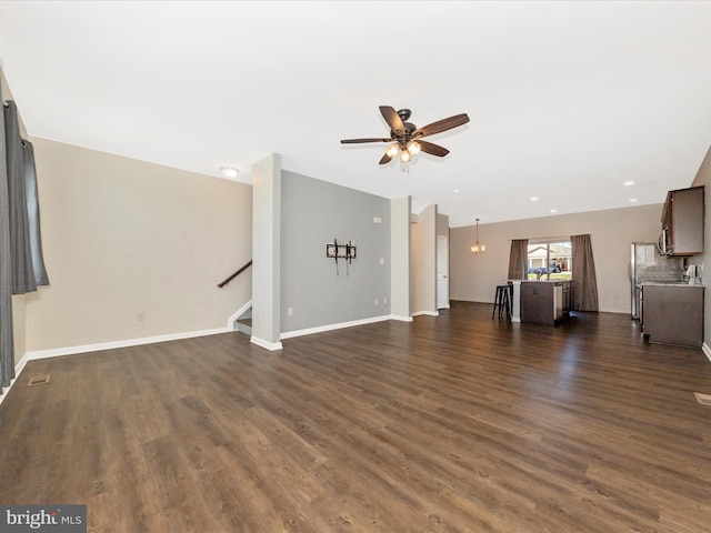 unfurnished living room with baseboards, a ceiling fan, stairs, and dark wood-style floors