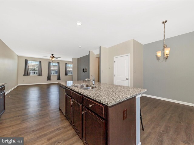 kitchen featuring dark wood-type flooring, a sink, baseboards, and ceiling fan with notable chandelier