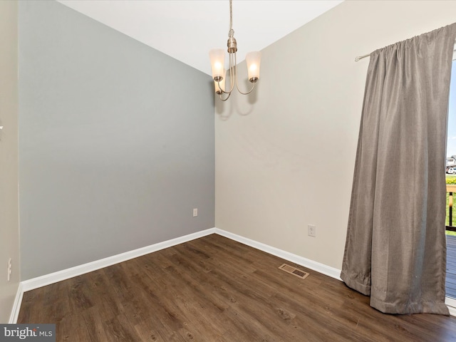 unfurnished room featuring an inviting chandelier, dark wood-style flooring, baseboards, and visible vents