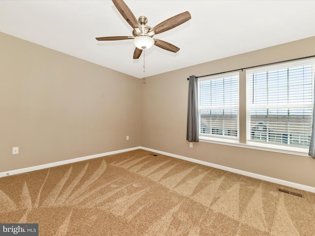 carpeted empty room with baseboards, ceiling fan, and visible vents