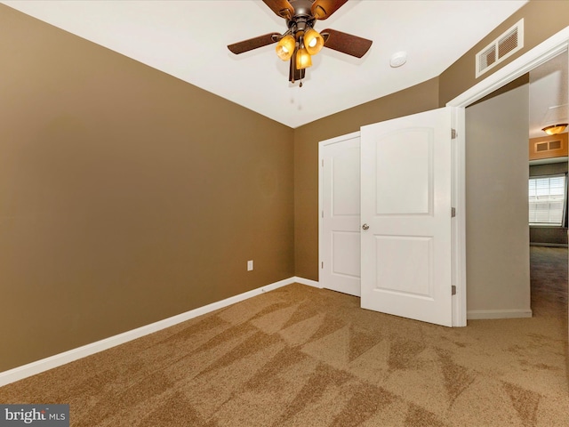 unfurnished bedroom with carpet flooring, baseboards, visible vents, and ceiling fan