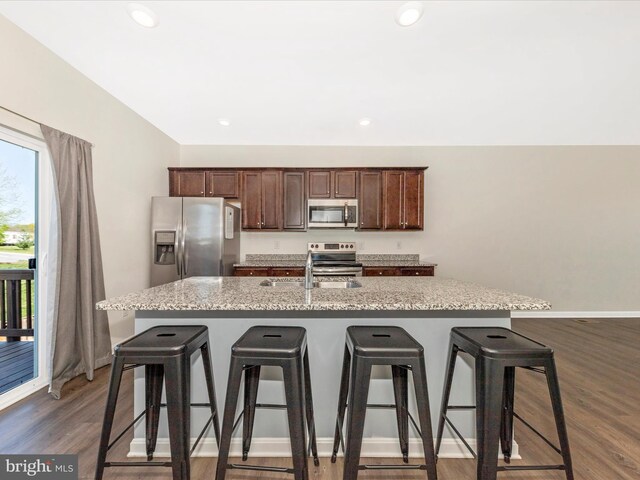 kitchen with a breakfast bar area, appliances with stainless steel finishes, a center island with sink, and a sink