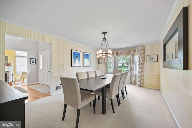 dining area with light carpet, ornamental molding, wallpapered walls, and a notable chandelier