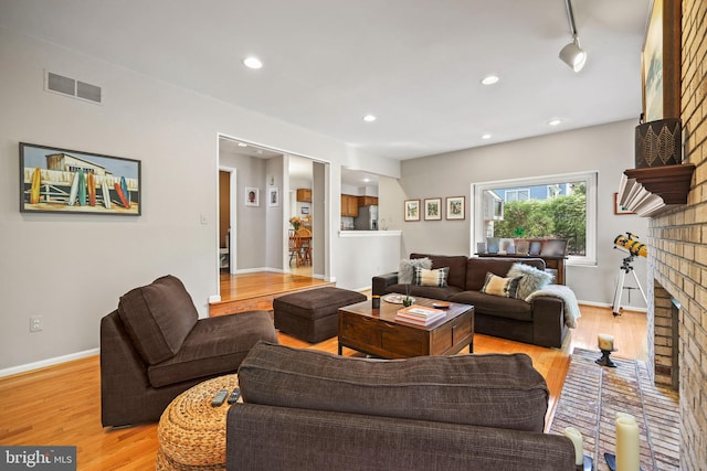 living room featuring baseboards, light wood-style flooring, and a fireplace
