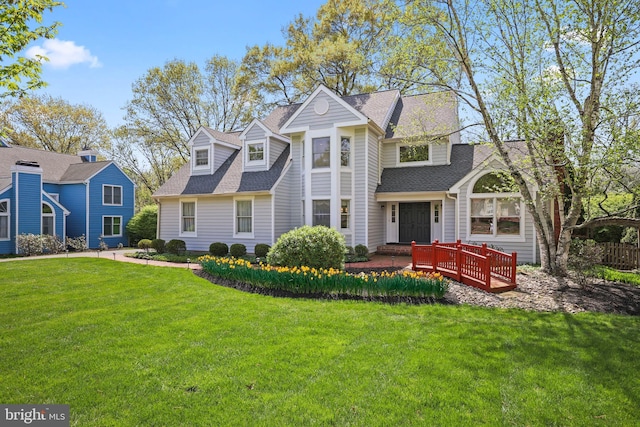 view of front of house featuring a shingled roof and a front lawn