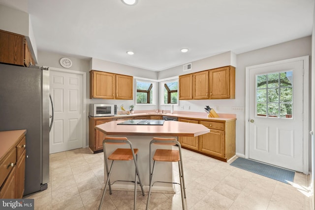 kitchen with stainless steel appliances, a wealth of natural light, a kitchen bar, and a kitchen island