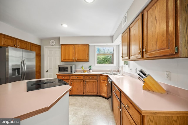 kitchen featuring brown cabinets, stainless steel appliances, light countertops, and a sink