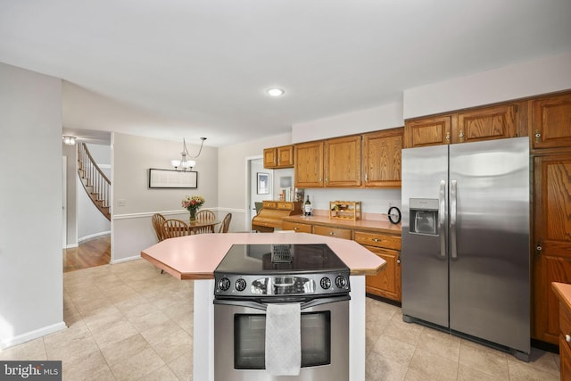 kitchen with brown cabinets, a notable chandelier, baseboards, light countertops, and appliances with stainless steel finishes