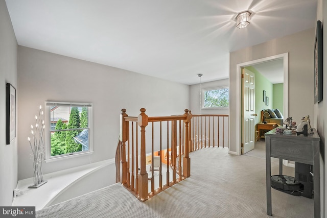 hallway with an upstairs landing and light carpet