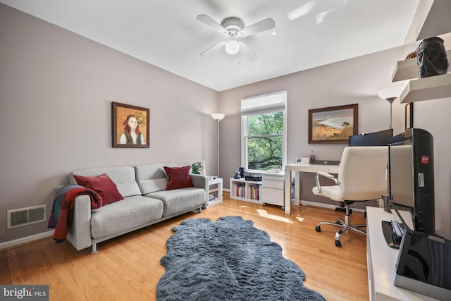 office space featuring baseboards, visible vents, a ceiling fan, and light wood finished floors