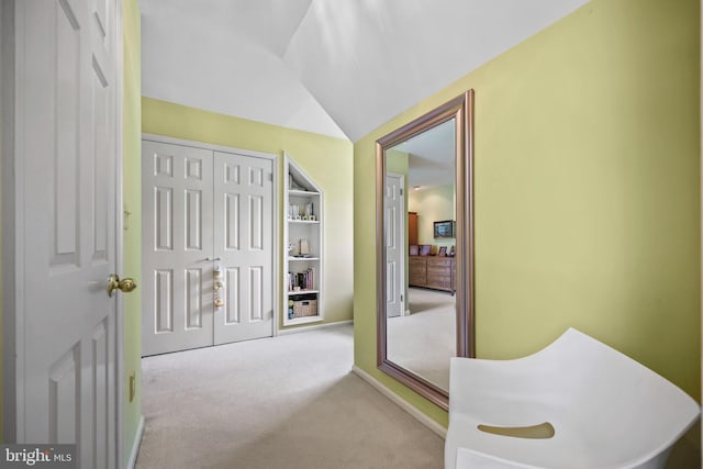 hallway featuring baseboards, carpet, and vaulted ceiling