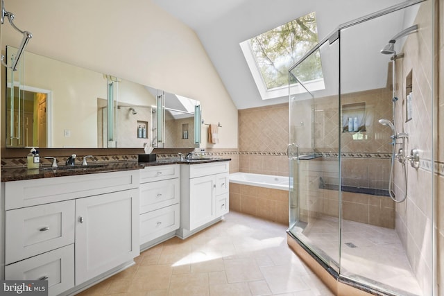 bathroom with a shower stall, vaulted ceiling with skylight, a sink, a garden tub, and tile patterned flooring