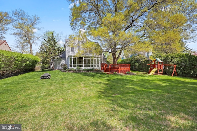 view of yard with fence, a deck, a playground, and a sunroom
