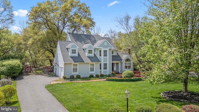 view of front of property featuring a shingled roof, a front lawn, driveway, and an attached garage