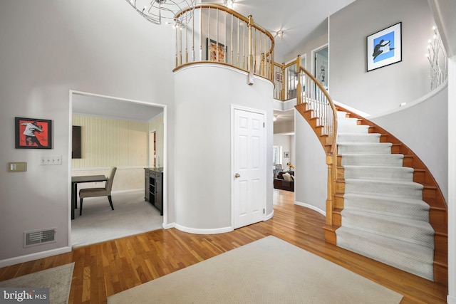 interior space with a towering ceiling, visible vents, wood finished floors, and baseboards