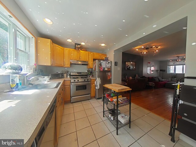 1231 S Clarion St, Philadelphia, PA 19147 - kitchen with stainless steel appliances, under cabinet range hood, light tile patterned flooring, a ceiling fan, and a sink