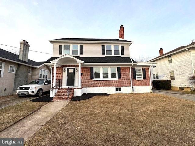 view of front facade with a chimney, a front lawn, and brick siding