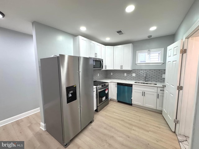 kitchen with light wood-type flooring, light countertops, white cabinets, a sink, and appliances with stainless steel finishes