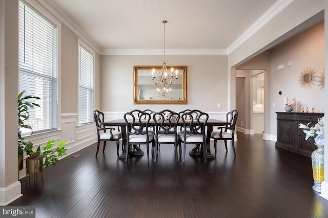 dining area with crown molding, dark wood-style flooring, an inviting chandelier, wainscoting, and visible vents