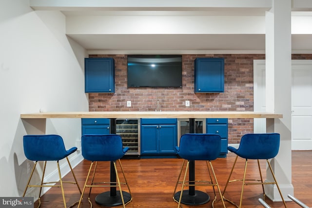 bar with wine cooler, dark wood-style floors, and brick wall