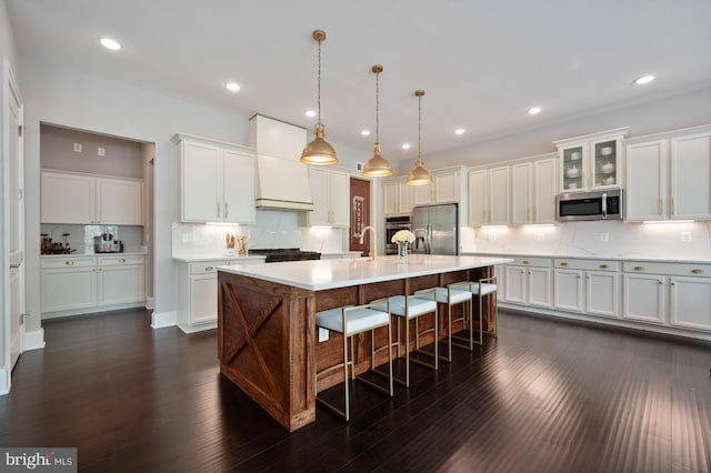 kitchen featuring white cabinets, appliances with stainless steel finishes, light countertops, a kitchen breakfast bar, and tasteful backsplash