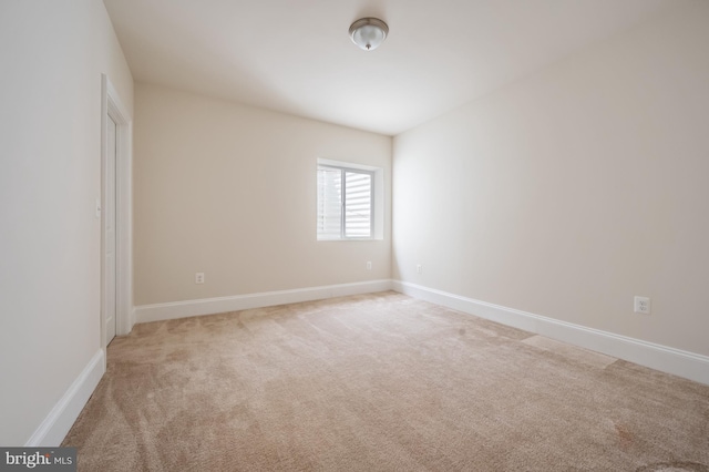spare room featuring baseboards and light carpet
