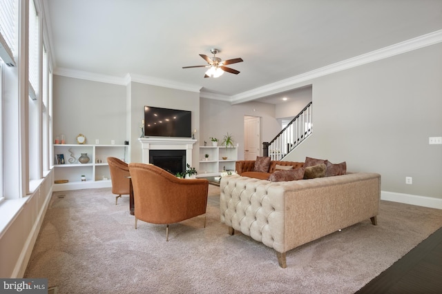 living room with carpet floors, crown molding, ceiling fan, and stairway