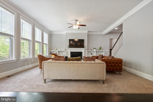living room with visible vents, crown molding, a fireplace, baseboards, and ceiling fan