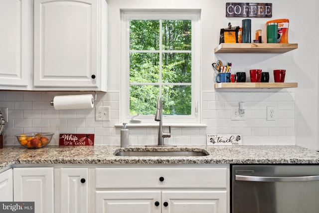 kitchen with stainless steel dishwasher, a sink, white cabinets, and decorative backsplash
