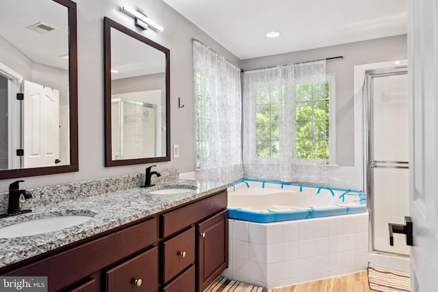 full bathroom with visible vents, a shower stall, a garden tub, and a sink