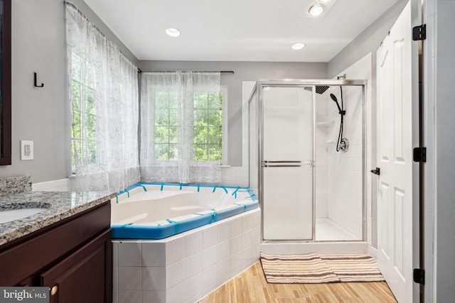 full bathroom with a bath, a shower stall, wood finished floors, and vanity