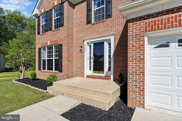view of exterior entry with brick siding and an attached garage