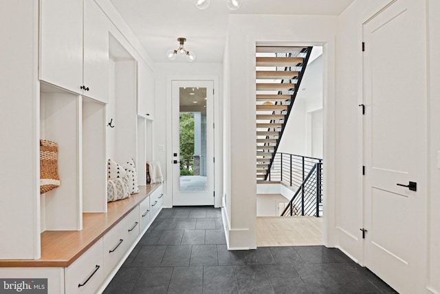 mudroom featuring dark tile patterned floors and an inviting chandelier