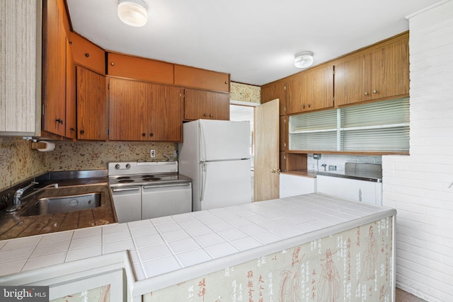 kitchen with electric stove, a sink, tile countertops, and freestanding refrigerator
