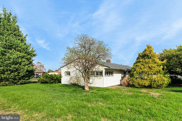 view of home's exterior featuring a lawn and a chimney