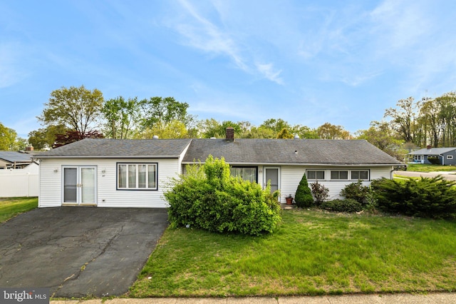 single story home with a chimney, fence, and a front lawn