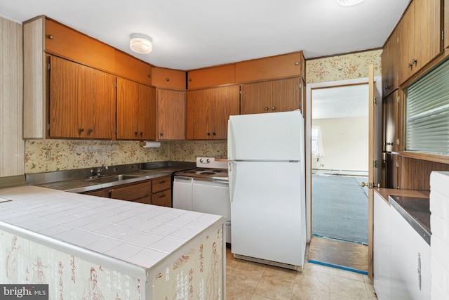 kitchen featuring range with electric cooktop, a sink, wallpapered walls, freestanding refrigerator, and a peninsula