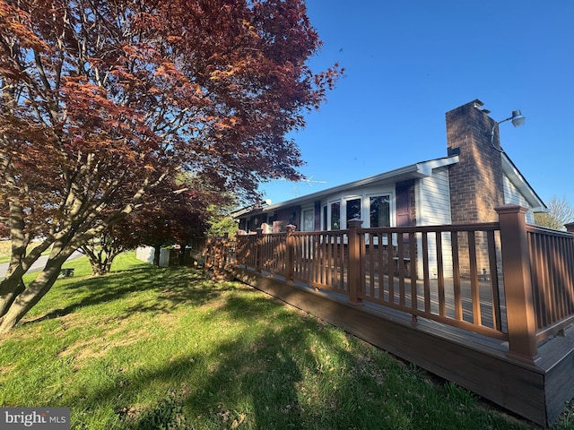 rear view of house with a lawn, a chimney, and a deck